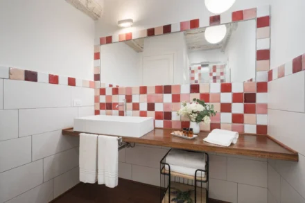 Bagno del B&B con lavabo moderno, grande specchio e parete decorata con piastrelle rosse e bianche